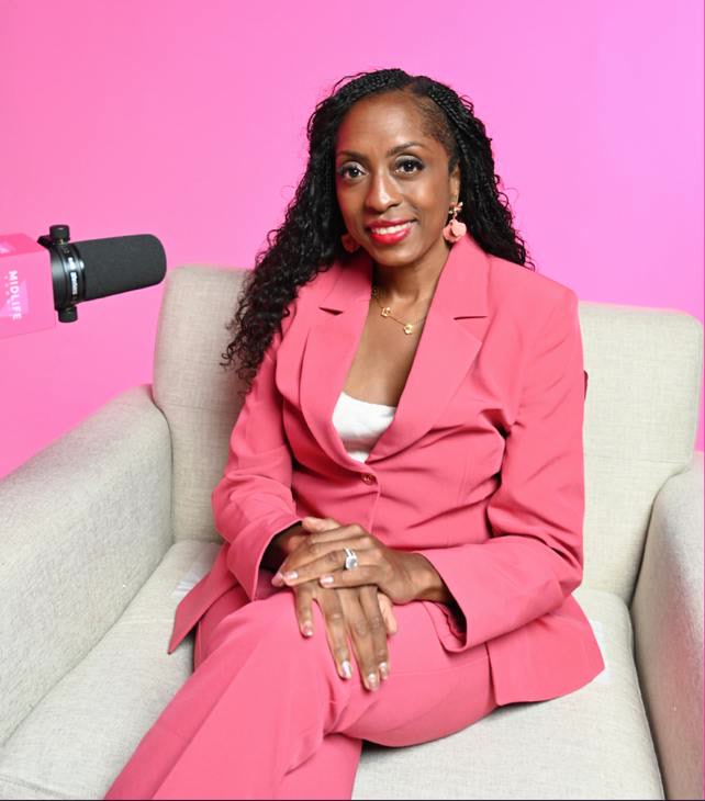 Dr. Eboni Cornish seated in a pink suit beside a microphone